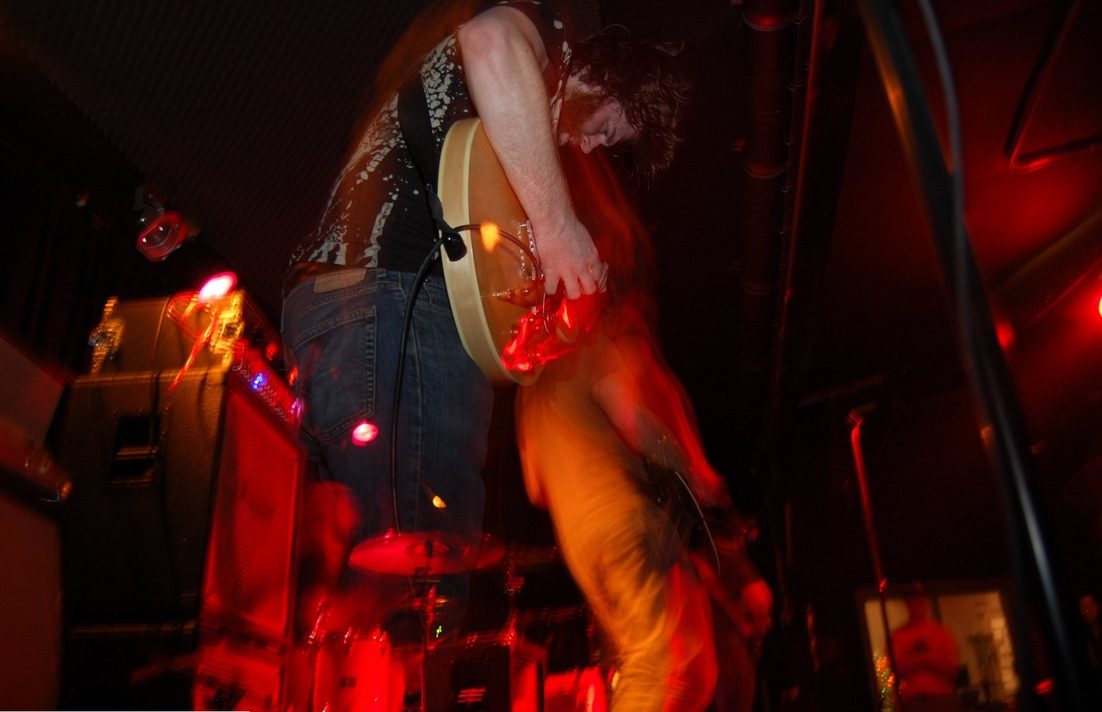 The TOSA guitarist playing live under red lights
